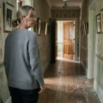 Femme contemplant un couloir sombre dans une vieille maison hantée aux murs tapissés de papier peint défraîchi